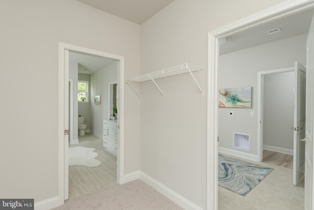 walk in closet featuring light carpet