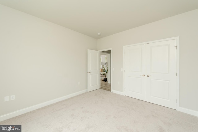 unfurnished bedroom featuring light carpet and a closet