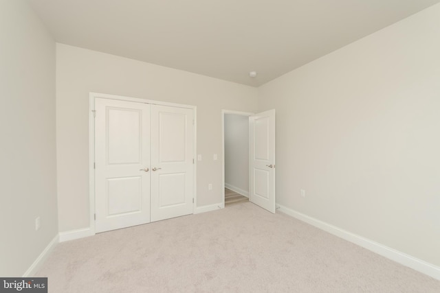 unfurnished bedroom with light colored carpet and a closet