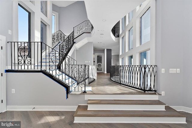 stairs featuring hardwood / wood-style floors and a high ceiling