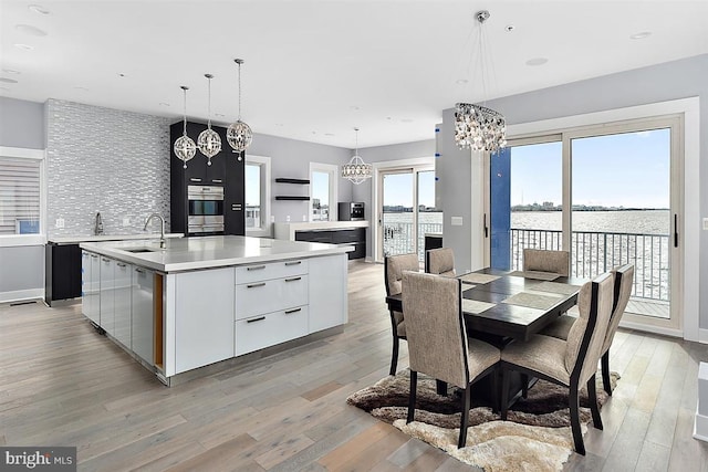 interior space featuring sink, a water view, a chandelier, and light wood-type flooring