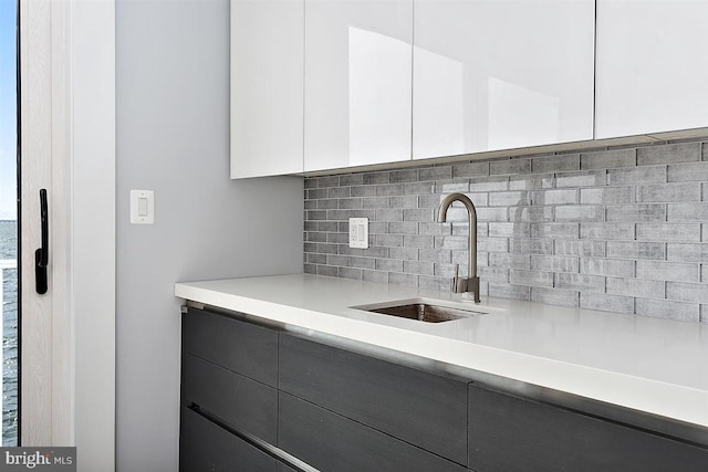 kitchen with white cabinetry, sink, and tasteful backsplash