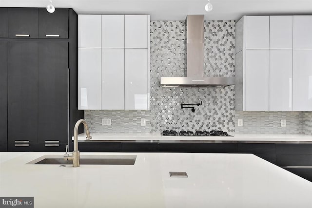 kitchen featuring wall chimney exhaust hood, white cabinetry, and backsplash