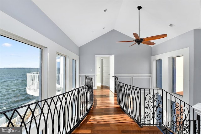 hallway featuring a water view, high vaulted ceiling, and dark wood-type flooring