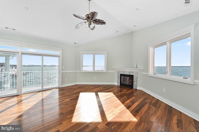 unfurnished living room featuring ceiling fan, dark wood-type flooring, a high end fireplace, vaulted ceiling, and a water view