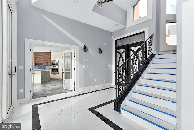 foyer featuring french doors, a healthy amount of sunlight, and a high ceiling