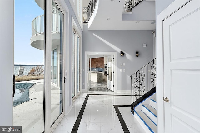 foyer entrance featuring a water view and a high ceiling