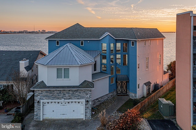 view of front of property featuring central AC, a water view, and a garage