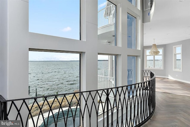 hallway with a water view, parquet flooring, and a high ceiling