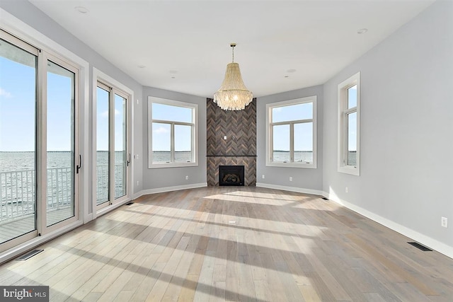 unfurnished living room with light hardwood / wood-style floors, a water view, and a wealth of natural light