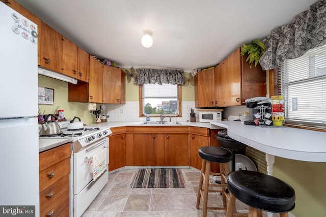 kitchen with tasteful backsplash, light tile floors, ventilation hood, white appliances, and sink