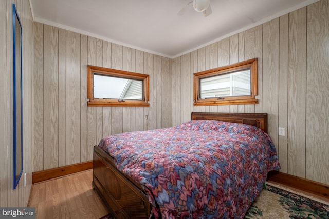 bedroom with wood walls, crown molding, ceiling fan, and light hardwood / wood-style flooring