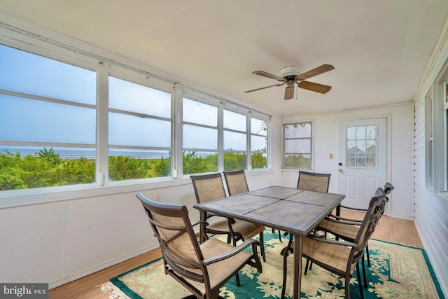 sunroom featuring ceiling fan and a water view