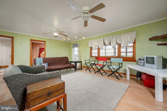 living room featuring light hardwood / wood-style floors, ceiling fan, and crown molding