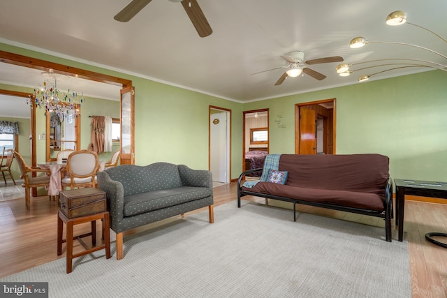 living room with crown molding, ceiling fan, and light wood-type flooring