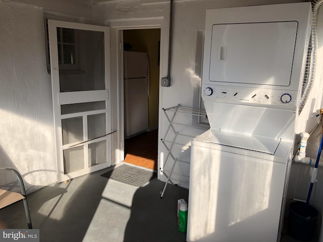 laundry area featuring stacked washer / dryer and wood-type flooring