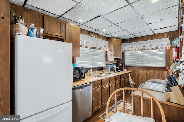 kitchen with appliances with stainless steel finishes, a drop ceiling, dark wood-type flooring, and sink