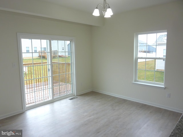 unfurnished room featuring a notable chandelier and light wood-type flooring