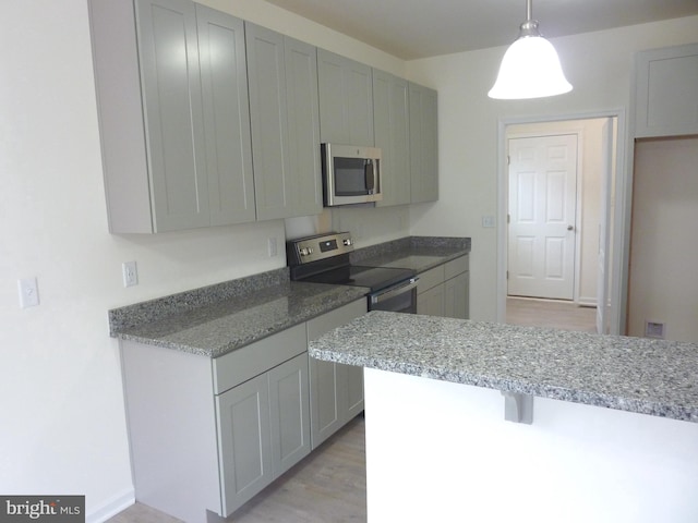 kitchen featuring decorative light fixtures, light wood-type flooring, stainless steel appliances, light stone counters, and gray cabinets