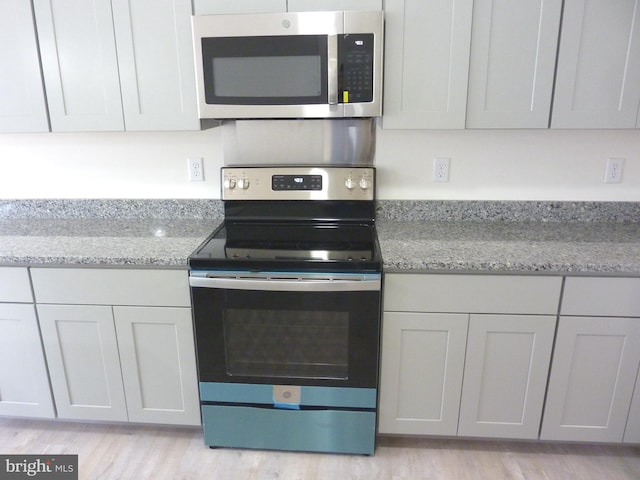 kitchen featuring light hardwood / wood-style floors, light stone counters, and stainless steel appliances