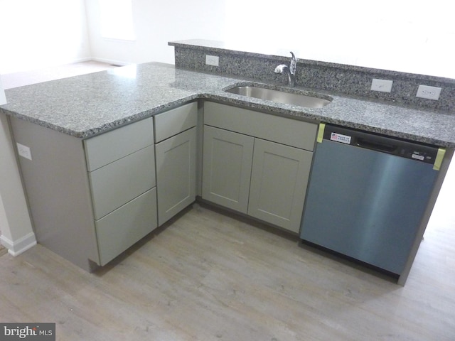 kitchen with stainless steel dishwasher, light wood-type flooring, light stone counters, sink, and gray cabinets