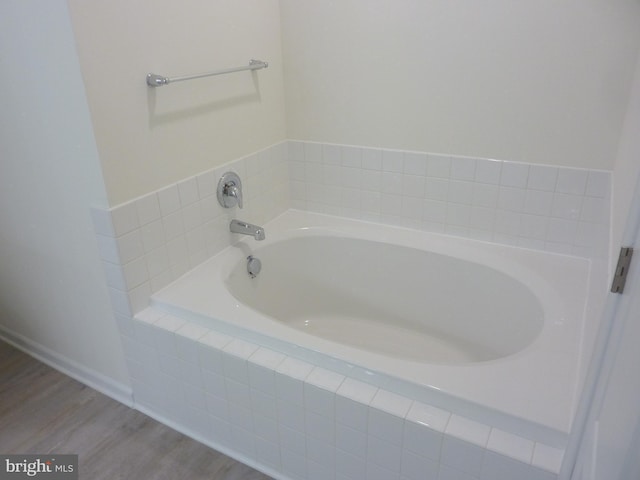 bathroom featuring wood-type flooring and a relaxing tiled bath