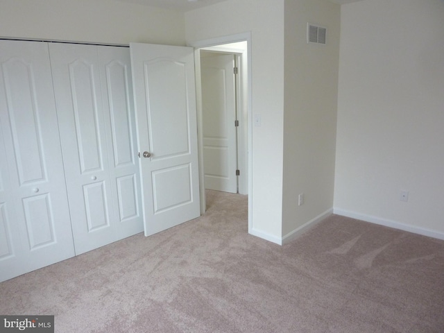 unfurnished bedroom featuring a closet and light colored carpet