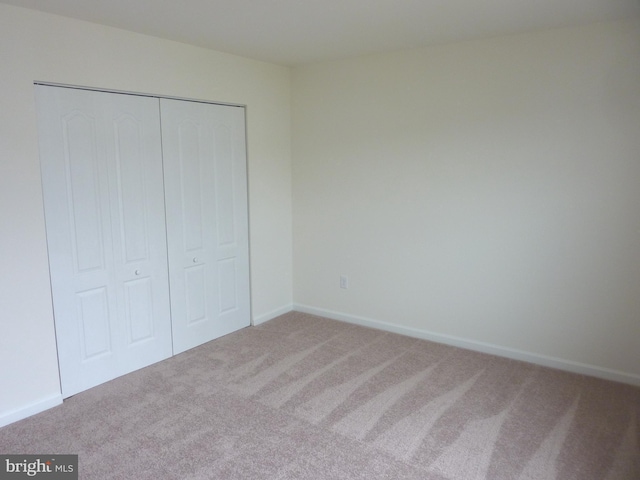 unfurnished bedroom featuring light colored carpet and a closet