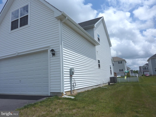 view of side of property with central air condition unit, a lawn, and a garage