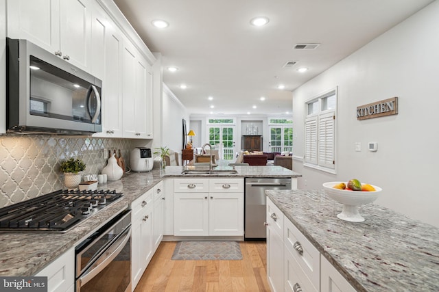 kitchen featuring sink, white cabinets, light hardwood / wood-style flooring, appliances with stainless steel finishes, and light stone countertops