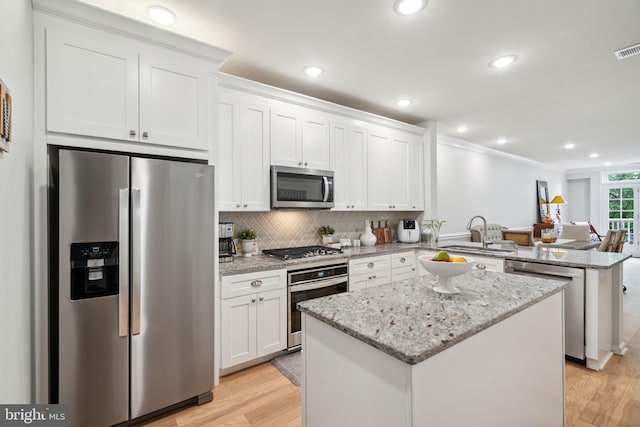 kitchen featuring stainless steel appliances, sink, white cabinetry, and a center island