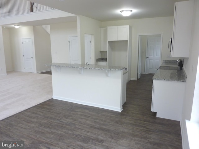 kitchen featuring dark carpet, light stone counters, a breakfast bar area, range, and white cabinets