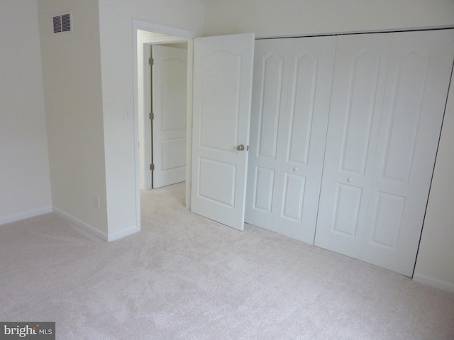 unfurnished bedroom with a closet and light colored carpet