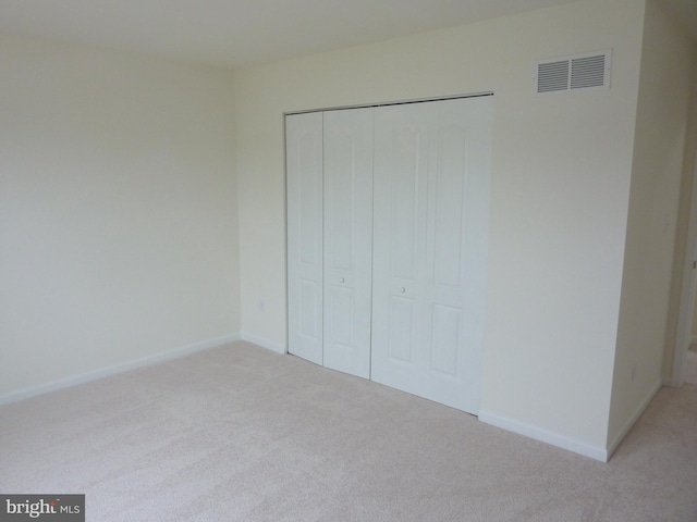 unfurnished bedroom featuring light colored carpet and a closet