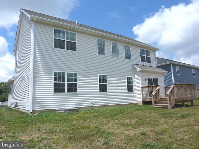 back of property featuring a wooden deck and a lawn