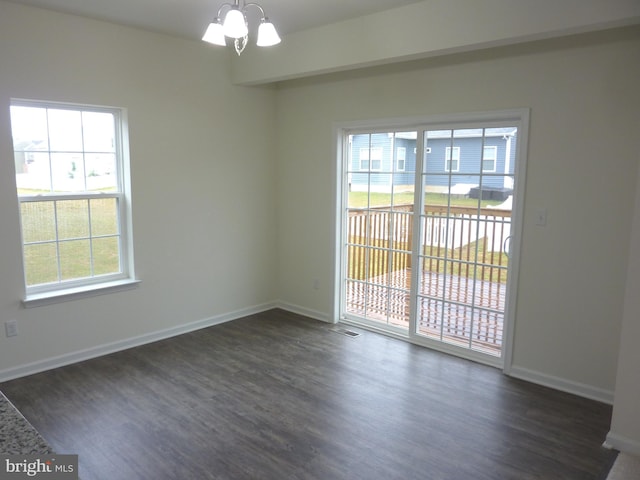 unfurnished room with a chandelier and dark hardwood / wood-style floors