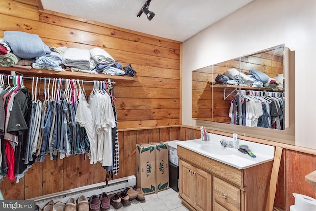 spacious closet with sink, a baseboard heating unit, and light tile flooring