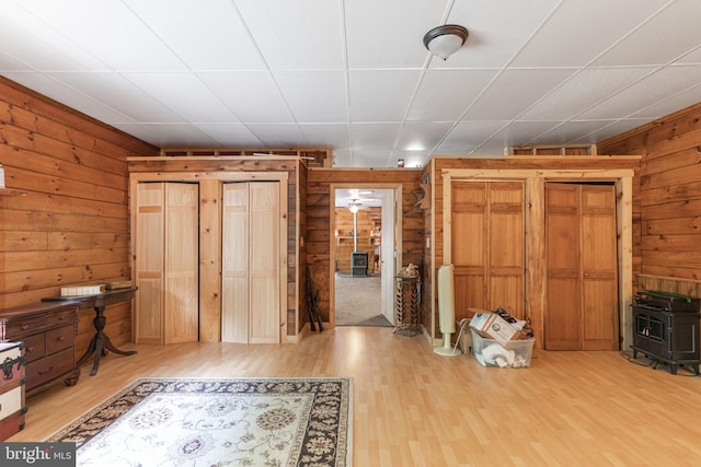 interior space featuring wooden walls, a wood stove, and light wood-type flooring