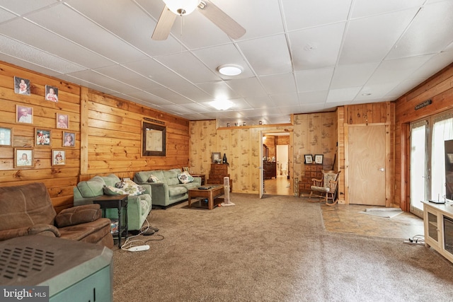 carpeted living room with wood walls and ceiling fan