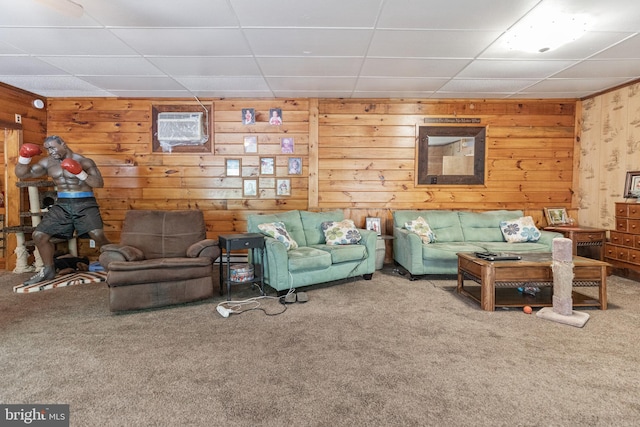 unfurnished living room featuring a drop ceiling, light carpet, and wood walls