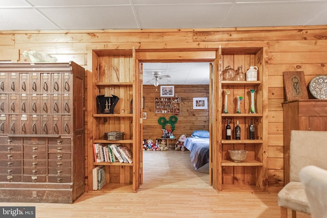 interior space featuring wood walls, a paneled ceiling, and light hardwood / wood-style flooring