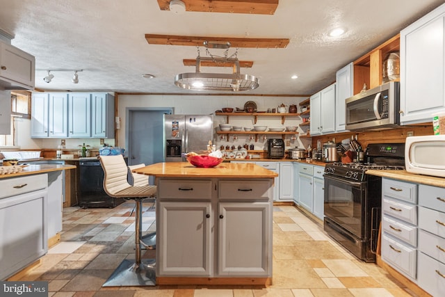 kitchen featuring a kitchen island, wood counters, light tile floors, and black appliances