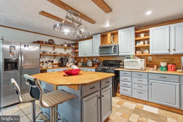 kitchen featuring a kitchen island, wood counters, light tile flooring, and stainless steel appliances