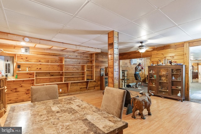 dining space featuring wood walls, light hardwood / wood-style floors, and ceiling fan