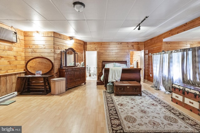 interior space featuring light hardwood / wood-style flooring, baseboard heating, a drop ceiling, and wood walls