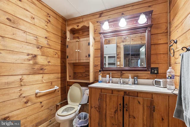 bathroom featuring wooden walls, toilet, and vanity