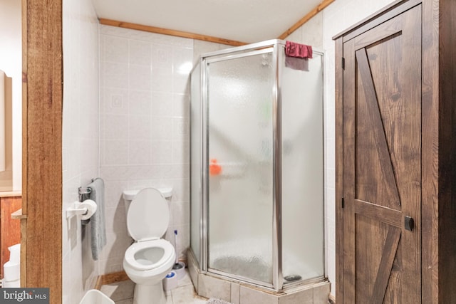 bathroom featuring tile walls, toilet, a shower with door, and tile flooring