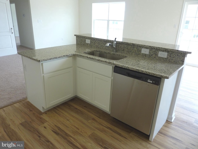 kitchen featuring light stone countertops, sink, hardwood / wood-style flooring, and dishwasher