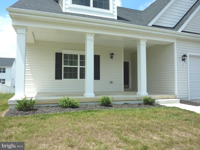 doorway to property featuring a lawn, covered porch, and a garage