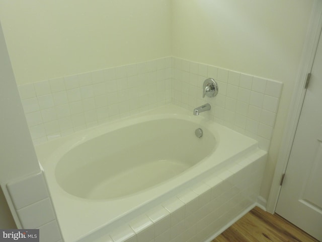 bathroom with tiled bath and hardwood / wood-style floors